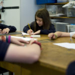 School children sitting around the table creating art