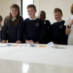 Children standing next to a table showing off there artwork