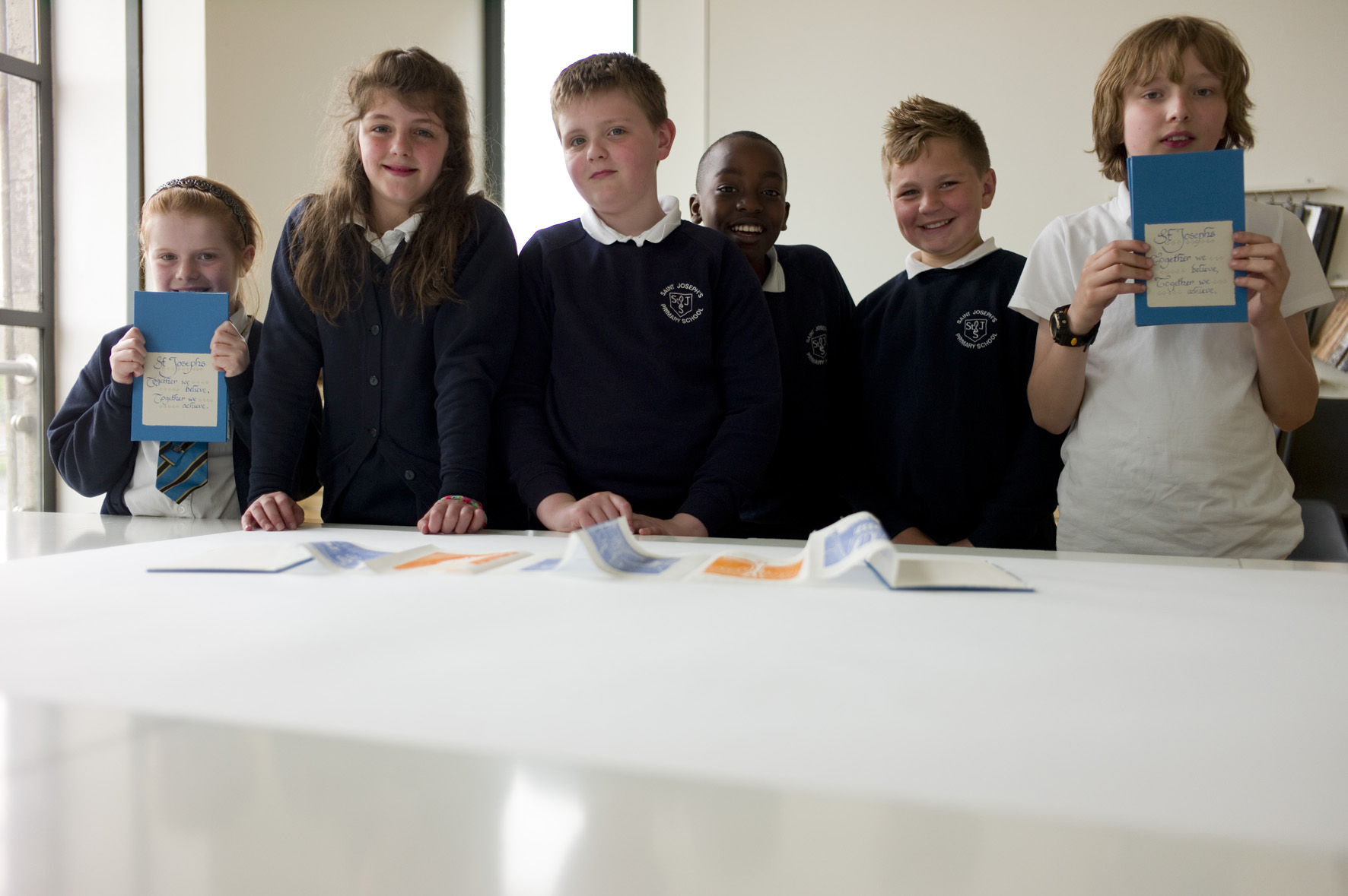 Children standing next to a table showing off there artwork