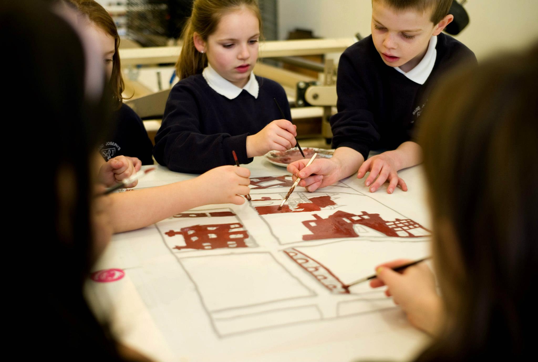 School children creating artwork around a table